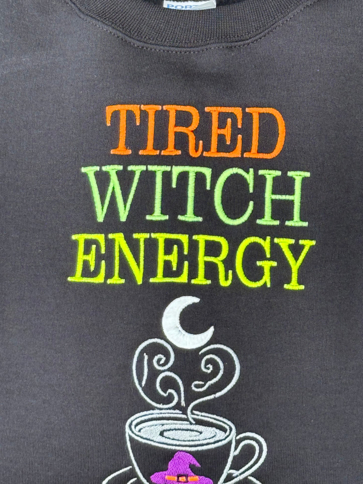 Black shirt with colorful text 'TIRED WITCH ENERGY' and a witch hat design.