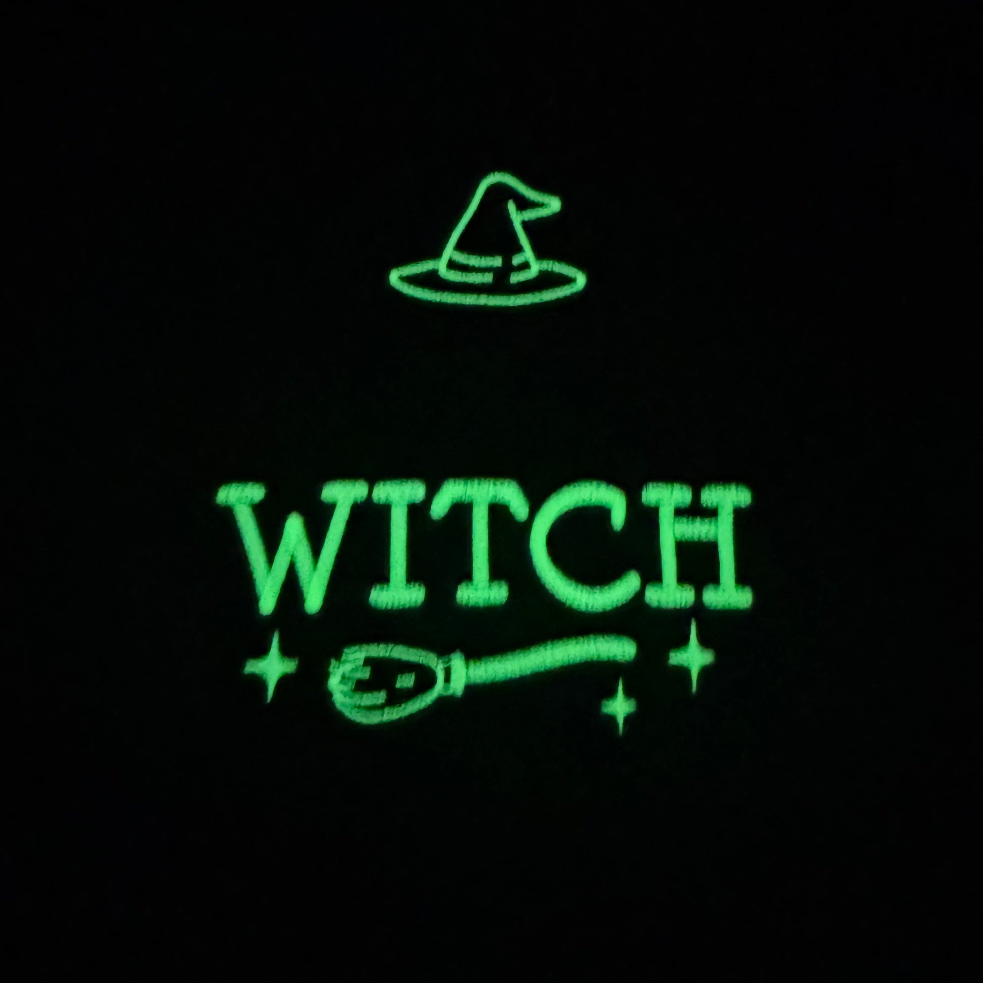 Glowing green text 'WITCH' with a broom and hat on a black background