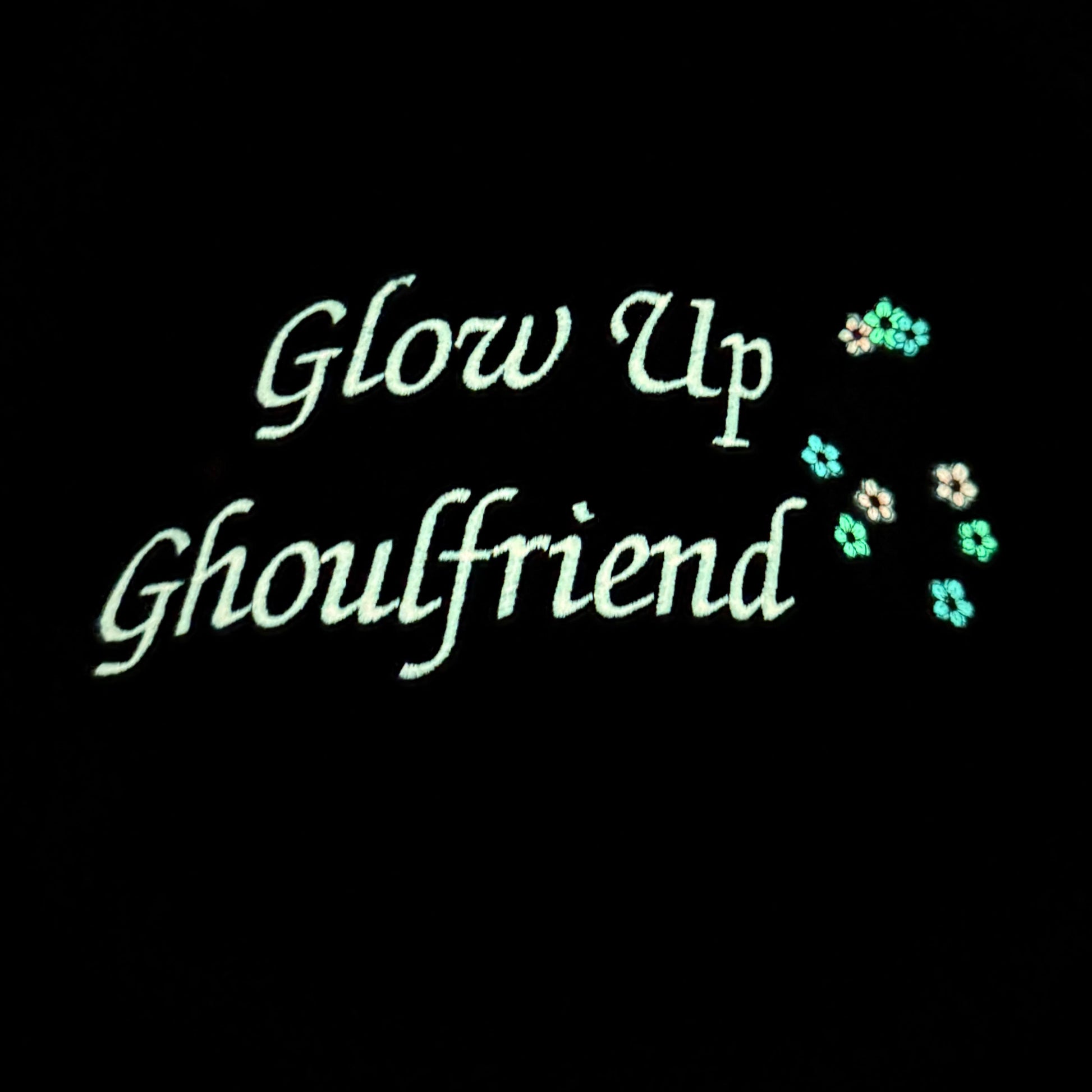 Glow Up Ghoulfriend text on a black background showing the glow in the dark thread.