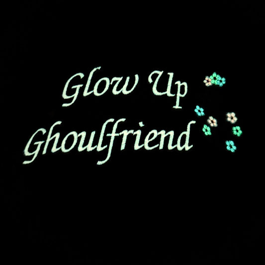 Glow Up Ghoulfriend text on a black background showing the glow in the dark thread.