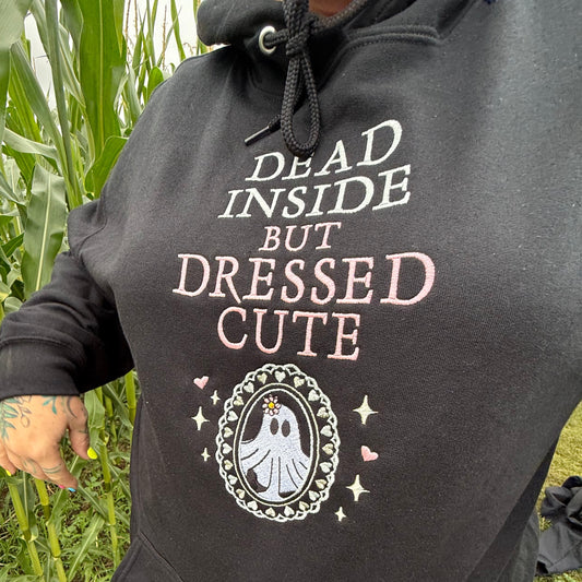 Person wearing a black hoodie with text and graphics, standing in a grassy area.